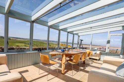 una grande stanza con un tavolo, sedie e finestre di Budle Newton - North East Escapes a Bamburgh