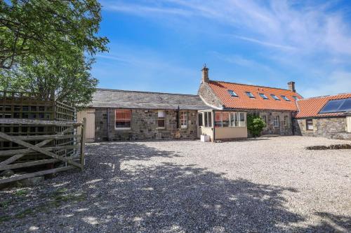 un vecchio edificio in pietra con cancello e fienile di Budle Newton - North East Escapes a Bamburgh