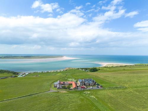 an aerial view of a house and the ocean at Budle Newton - North East Escapes in Bamburgh