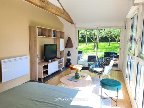 Cette chambre comprend un lit, une télévision et un salon. dans l'établissement Le Hameau 2 gîtes pour 15 personnes nature et rivière proche du Puy duFou, à La Forêt-sur-Sèvre
