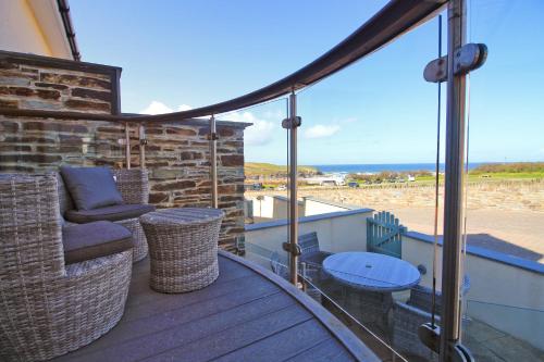 einen Balkon mit einem Sofa und einem Tisch auf einer Terrasse in der Unterkunft BY THE BEACH, The Quies, Beach House in Saint Merryn