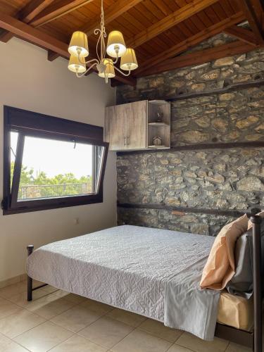 a bedroom with a bed and a stone wall at Villa Dionisos in Skotína