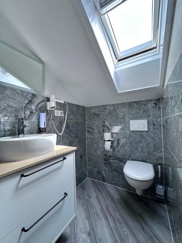 a bathroom with a sink and a toilet and a skylight at Mertinkus Nordseehotel in Cuxhaven