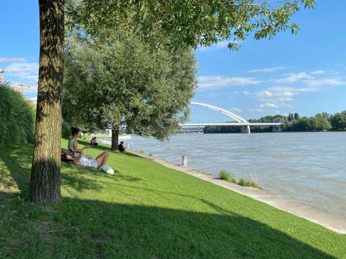 a person sitting on the grass next to the water at Eurovea Apartments in Bratislava