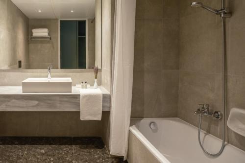 a bathroom with a sink and a bath tub at Amalia Hotel Delphi in Delfoi