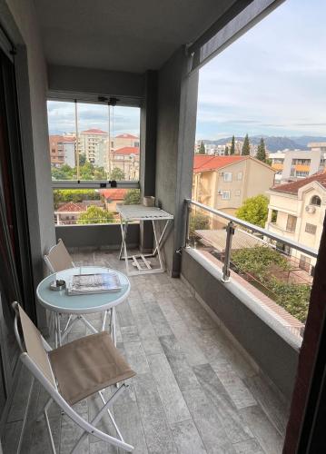 a balcony with a table and chairs and a large window at DOWNTOWN apartment Old Town in Podgorica