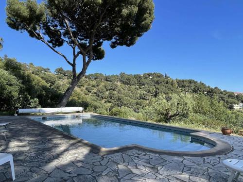 une piscine avec un arbre en arrière-plan dans l'établissement Maison T4 avec Piscine Privée – Bormes-les-Mimosas - FR-1-308-209, à Bormes-les-Mimosas