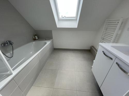 La salle de bains blanche est pourvue d'une baignoire et d'une fenêtre. dans l'établissement Maison moderne pour 8 pers., proche plage, Arzon, au calme, avec WiFi - FR-1-775-28, à Arzon