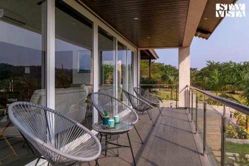 a group of chairs sitting on a porch at StayVista's The Tavern At Canary Farms - Mountain-View Luxury Mansion with Infinity Pool & Games Zone in Lonavala