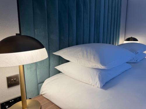 a bedroom with a bed with pillows and a lamp at The Lodge Hotel - Putney in London