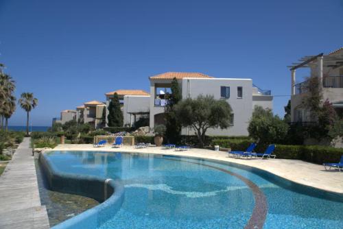 una gran piscina con sillas azules y una casa en Elias 1-Bedroom Apartment on the beach with pool, en La Canea
