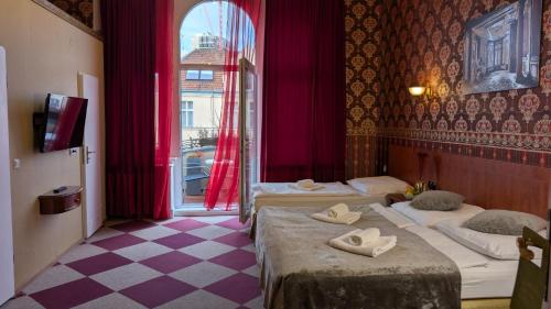 Una habitación de hotel con dos camas y una ventana. en Hotel Pension Bella, en Berlín