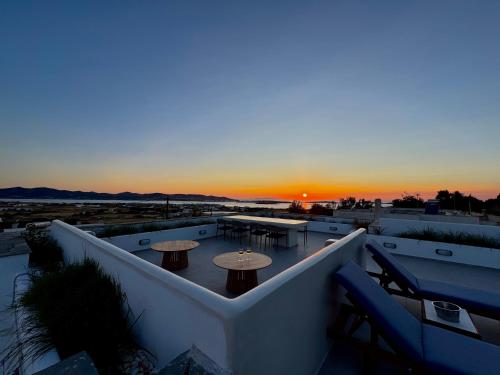 a sunset on a rooftop with tables and tables at La vie est belle luxury apartment BBQ jacuzzi&view in Pounda