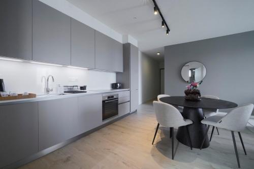 a kitchen with a black table and white cabinets at Rooftop Sunset Garden by Staycom in Pamboula
