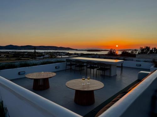a rooftop deck with tables and chairs and a sunset at La vie est belle luxury apartment BBQ jacuzzi&view in Pounda