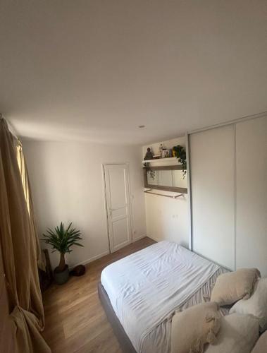 une chambre avec un lit blanc et une plante dans l'établissement Le calme de Daumesnil, à Paris