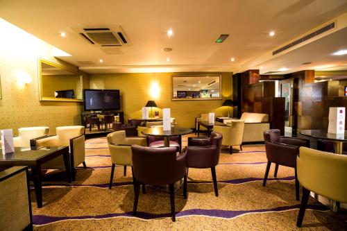 a hotel lobby with tables and chairs and a television at Crowne Plaza London Ealing by IHG in London