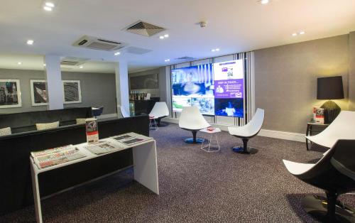 a waiting room with chairs and a table and a screen at Crowne Plaza London Ealing by IHG in London