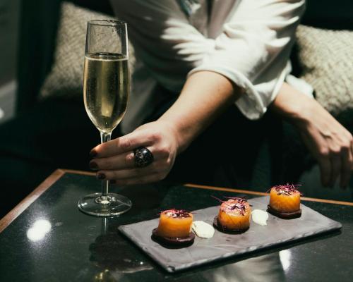 a person holding a glass of wine and a plate of food at Crowne Plaza London Ealing by IHG in London
