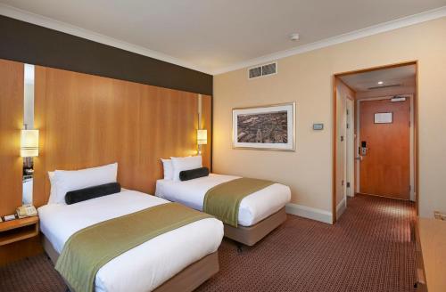a hotel room with two beds and a hallway at Crowne Plaza London Ealing by IHG in London