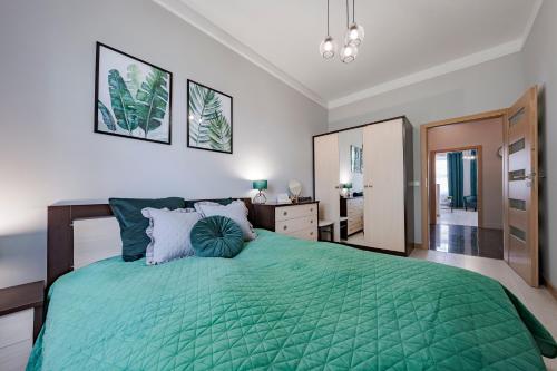 a bedroom with a bed with a green comforter at Amber Apartments in Gdańsk