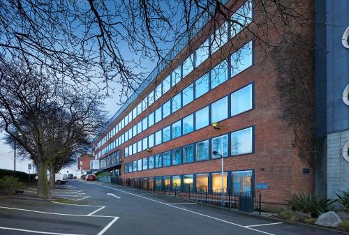 a large brick building with many windows on a street at Crowne Plaza London Ealing by IHG in London