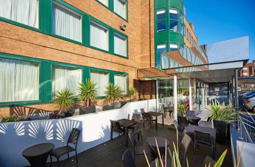 a patio with chairs and tables and a building at Crowne Plaza London Ealing by IHG in London