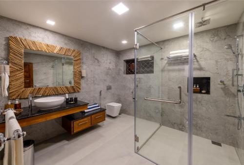 a bathroom with a glass shower and a sink at Tranquil Resort - Blusalzz Collection, Wayanad - Kerala in Ambalavayal