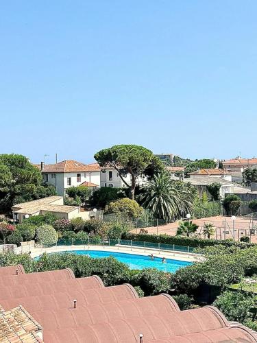 Elle offre une vue sur une piscine bordée d'arbres et de maisons. dans l'établissement Superbe Appartement 1 chambres, 2 Tennis, 2 Piscines, plages, Parking, à Antibes