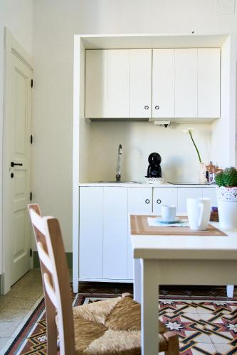 a kitchen with white cabinets and a table at Casa Zizzi - appartamento romantico per 2 in Puglia in Montalbano
