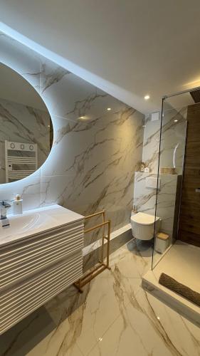 La salle de bains en marbre est pourvue d'un lavabo et de toilettes. dans l'établissement DUPLEX VUE MER Bord de plage Dernier étage, à Gassin