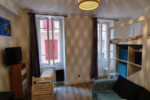 un salon avec un canapé et deux fenêtres dans l'établissement Appartement en plein centre de Collioure à 30 mètres de la plage, à Collioure