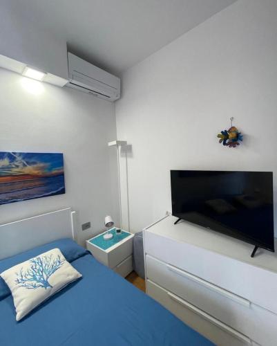 a bedroom with a blue bed and a flat screen tv at Condominio Roberta in Marinella di Sarzana