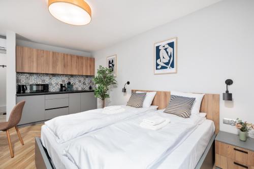 a bedroom with a large white bed and a kitchen at Nowy Hotel Monika - by Upstairs in Kraków