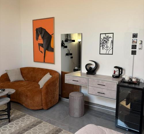 ein Wohnzimmer mit einer braunen Couch und einem Schreibtisch in der Unterkunft A new studio near the airport in Quai
