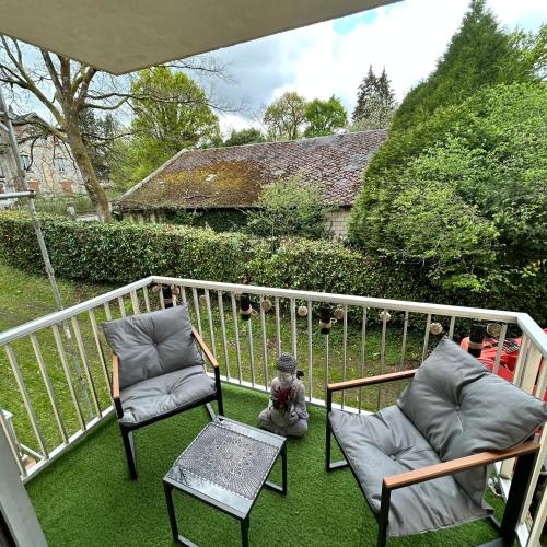 un ours en peluche assis entre deux chaises sur un balcon dans l'établissement Studio au calme avec stationnement, à Bagnoles-de-l'Orne