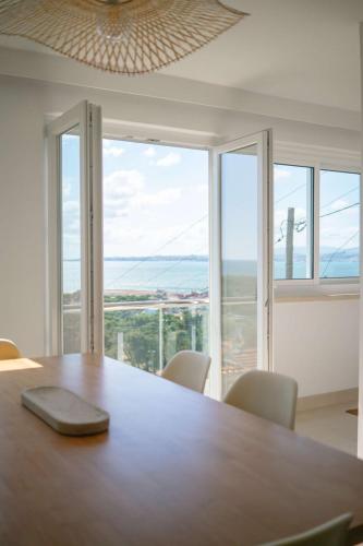 a large wooden table with chairs and a large window at Dreamview Nest | By Airnest in Trafaria