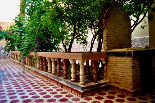 a wooden bench next to a brick wall with trees at Sunny City Villa with a Garden in Erfoud