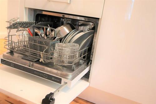 a dishwasher with dishes in it in a kitchen at Self check-in spacious apartment in a quiet area in Rīga
