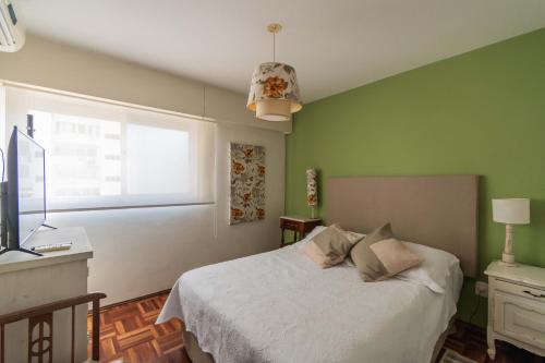 Un dormitorio con una cama con paredes verdes y una ventana en EL MEJOR LUGAR Departamento de Diseño en el mejor Barrio de Montevideo, en Montevideo
