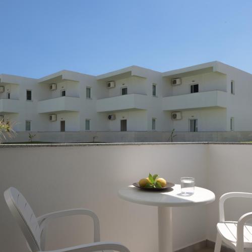 a table and chairs on a balcony with a building at Reina Apartments in Georgioupolis