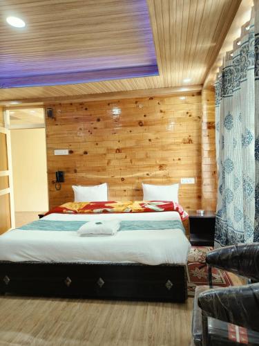 a bedroom with a large bed with a wooden wall at RR Homestay Chitkul in Chitkul