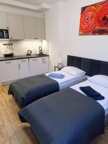 two beds in a room with a kitchen at Apartamenty u Portera w Centrum in Gdynia