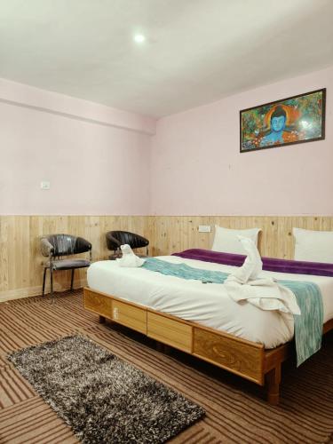 a bedroom with a large bed and two chairs at RR Homestay Chitkul in Chitkul