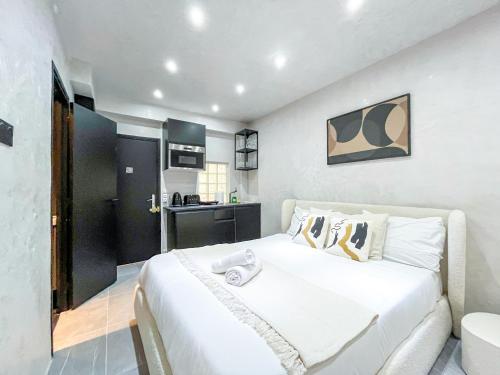 une chambre avec un grand lit blanc et une cuisine dans l'établissement Urban Flat 11 - Studio Wagam Pereire, à Paris