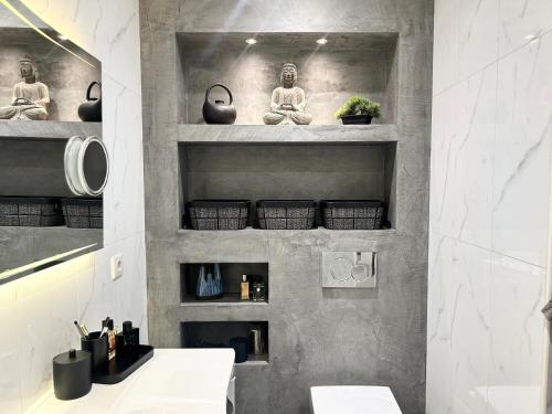 une salle de bain avec un lavabo et des étagères avec des méditants dans l'établissement Magnifique appartement - Vue mer, à Nice