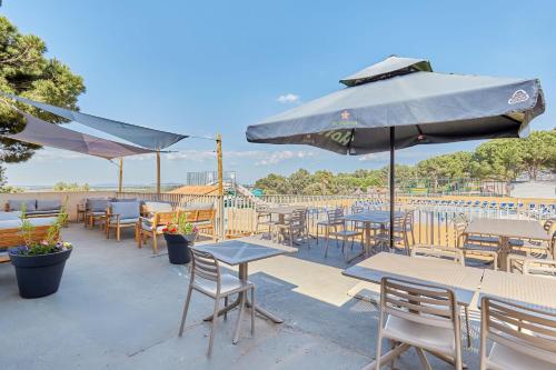 un patio avec tables, chaises et un parasol dans l'établissement Domaine Résidentiel de Plein Air Odalys La Pinède, à Agde