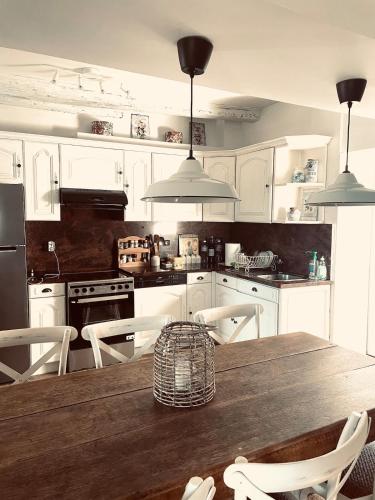 une cuisine avec une table en bois et des armoires blanches dans l'établissement Large charming house surrounded by nature, à Brassac