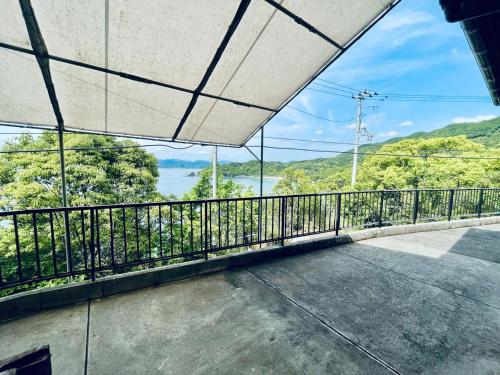 a balcony with a view of the water at ぽつんとオーシャンビューでバーベキューも出来る1日1組貸切宿カゴヤブハウス in Otsuki
