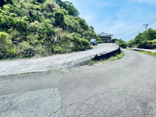 an empty road with a car driving down the road at ぽつんとオーシャンビューでバーベキューも出来る1日1組貸切宿カゴヤブハウス in Otsuki